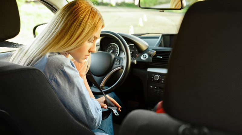 Student fastens seat belt in car, driving school